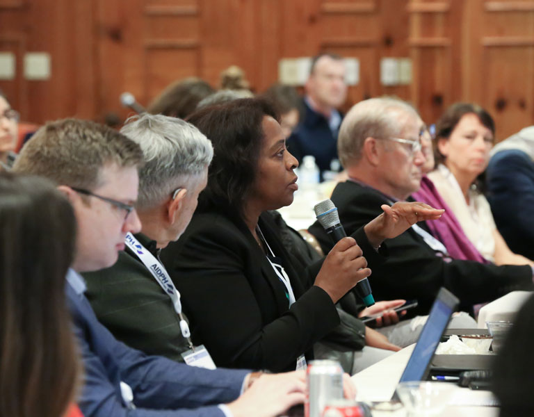 Attendee with microphone at crowded AIDPH conference posing insightful questions